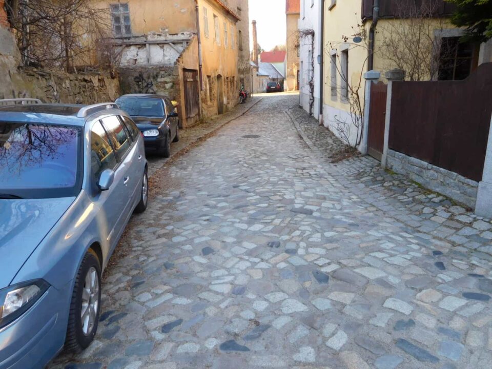 Kopfsteinpflasterstraße 
mit parkenden Autos: Straßensanierung mit ProVI